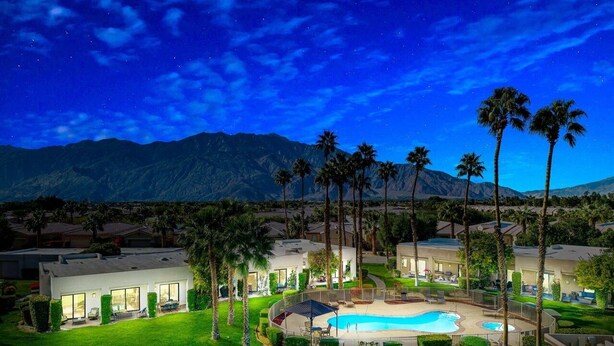 Ein Resort mit Swimmingpool, Palmen und einem Berg im Hintergrund.