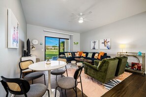 A modern living room with a sofa, chairs, a dining table, and artwork on the walls.