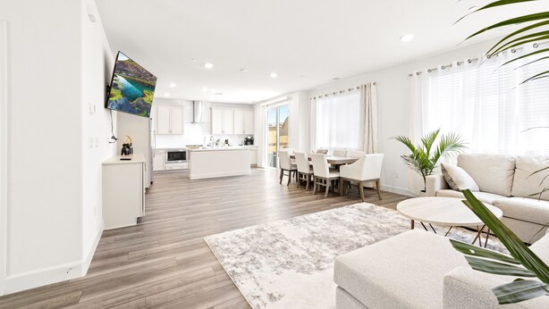 Un salon moderne comprenant un canapé, une table basse et un coin repas avec des chaises.