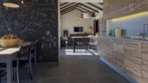 A modern kitchen with a chalkboard wall, wooden cabinets, and a dining area with a table and chairs.