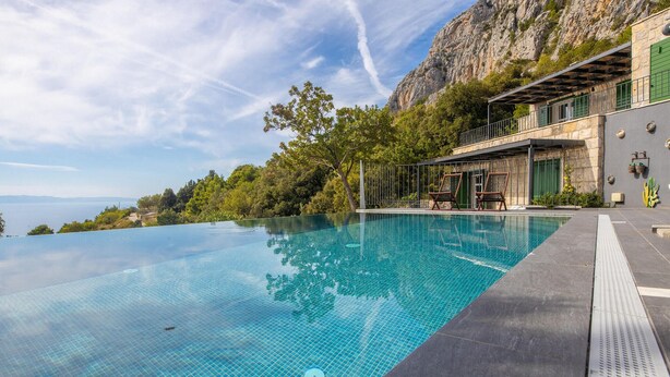 An infinity pool with a clear view of the sea and a rocky cliff.
