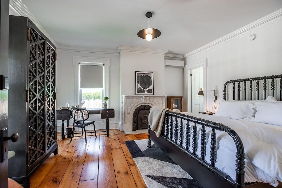 Ein Schlafzimmer mit einem Bett, einem Kamin, einem Schreibtisch mit Stuhl und einem Fenster.