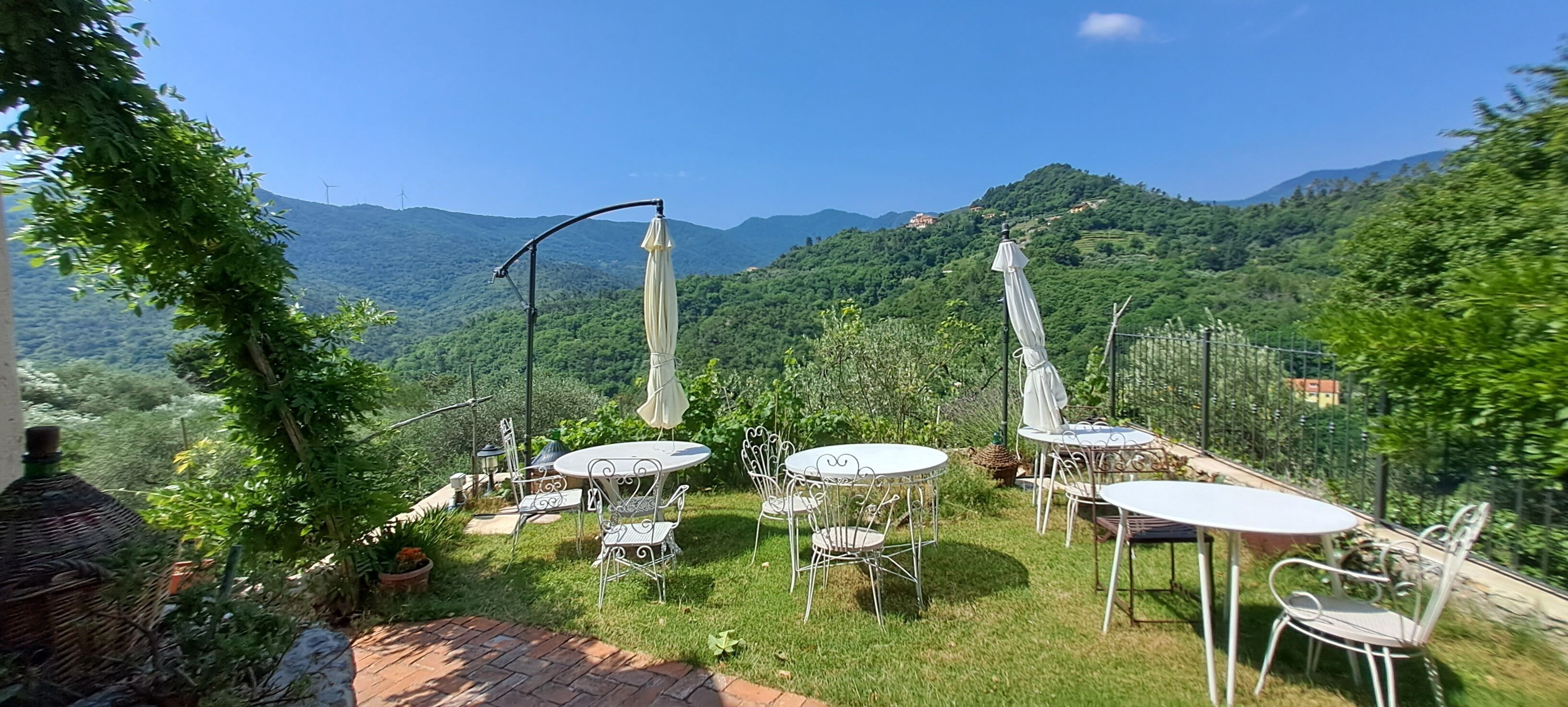 A patio with outdoor seating and a view of a mountainous landscape.
