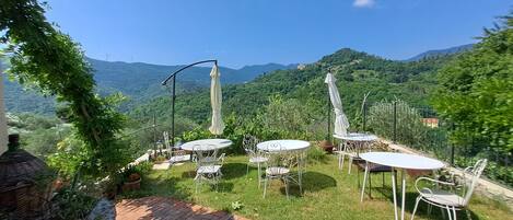 A patio with outdoor seating and a view of a mountainous landscape.