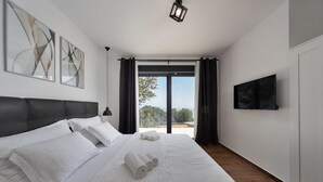 Een moderne hotelkamer met een groot bed, een flatscreen televisie en uitzicht op de omgeving.