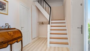 Un escalier avec des marches en bois et des murs blancs, menant à l’étage supérieur.