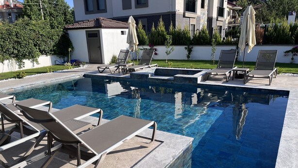 Une piscine avec des chaises longues et un petit bâtiment en arrière-plan.