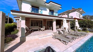Une maison à deux étages dotée d’une piscine, d’un espace salon extérieur et d’une terrasse couverte.