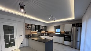 Une cuisine moderne dotée d’un îlot central, d’appareils électroménagers intégrés et d’un design épuré.
