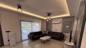 Un salon moderne avec un canapé d’angle, une table basse et un téléviseur posé sur un meuble.
