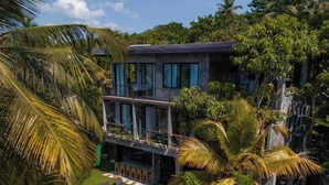 A modern building with a pool, surrounded by lush greenery and palm trees. - Gaia Soul  (Maaliyadda)