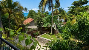 A tropical garden with palm trees, a stone pathway, and a building with a red roof. - Gaia Soul  (Maaliyadda)