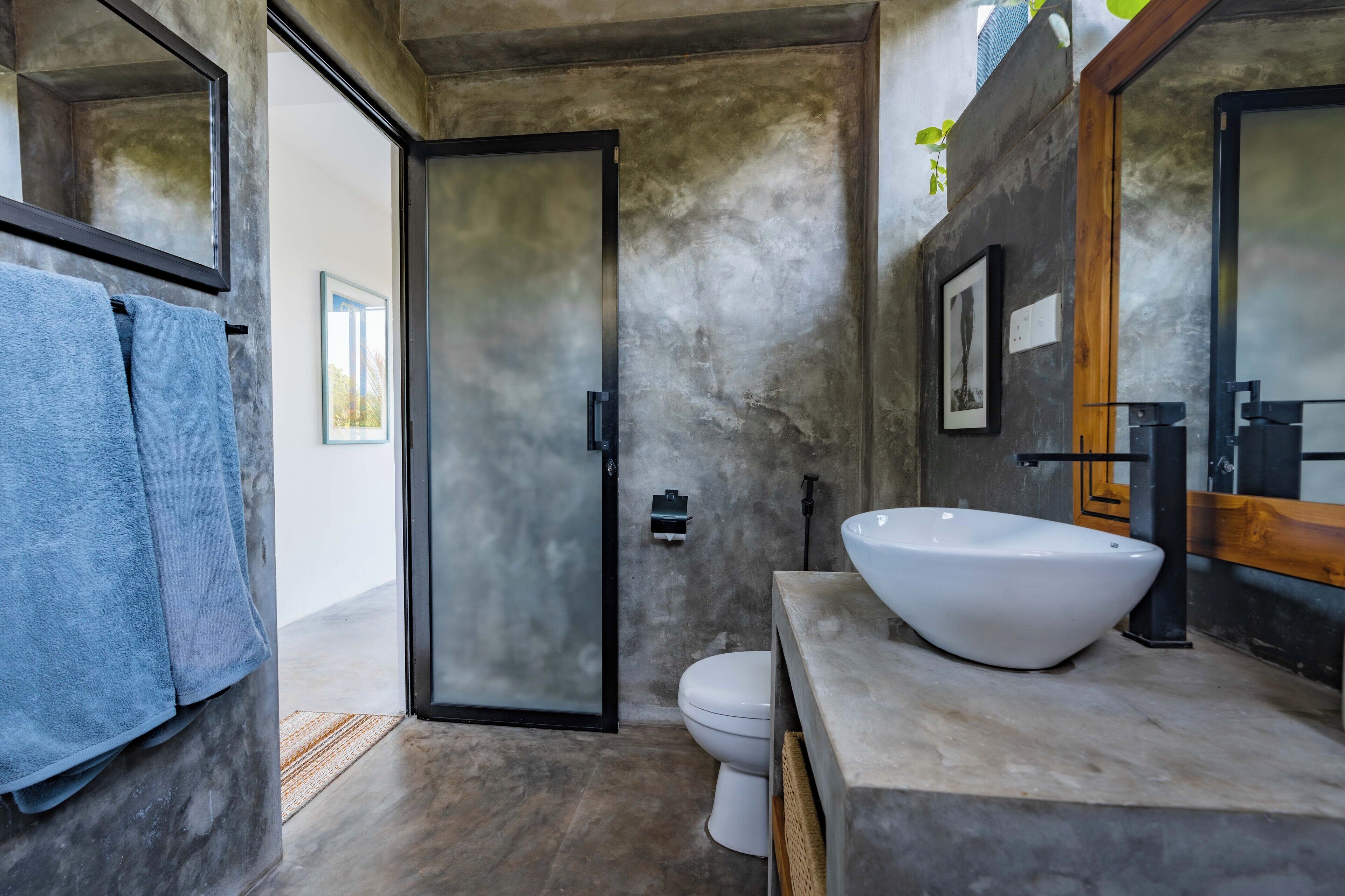 A modern bathroom with a large white sink, a toilet, and a shower area.