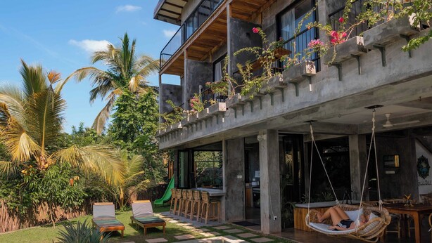 A modern house with a swimming pool, outdoor seating, and lush greenery. - Gaia Soul  (Maaliyadda)