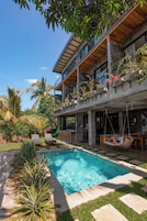 A modern house with a swimming pool, outdoor seating, and lush greenery.