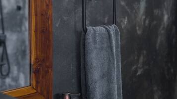 Ein Badezimmer mit einem weißen Waschbecken, einem spiegel mit Holzrahmen und einem Handtuch an einem schwarzen Handtuchhalter.