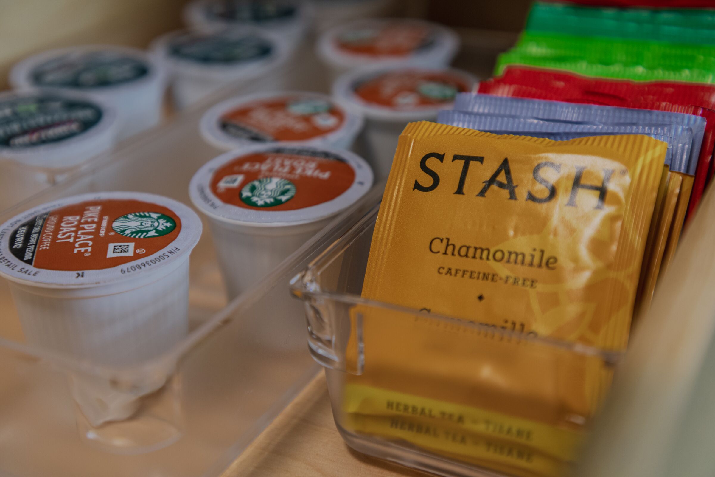 Een overzicht van verschillende koffiekapsules, waaronder een zichtbaar pakje 'STASH Kamille'.
