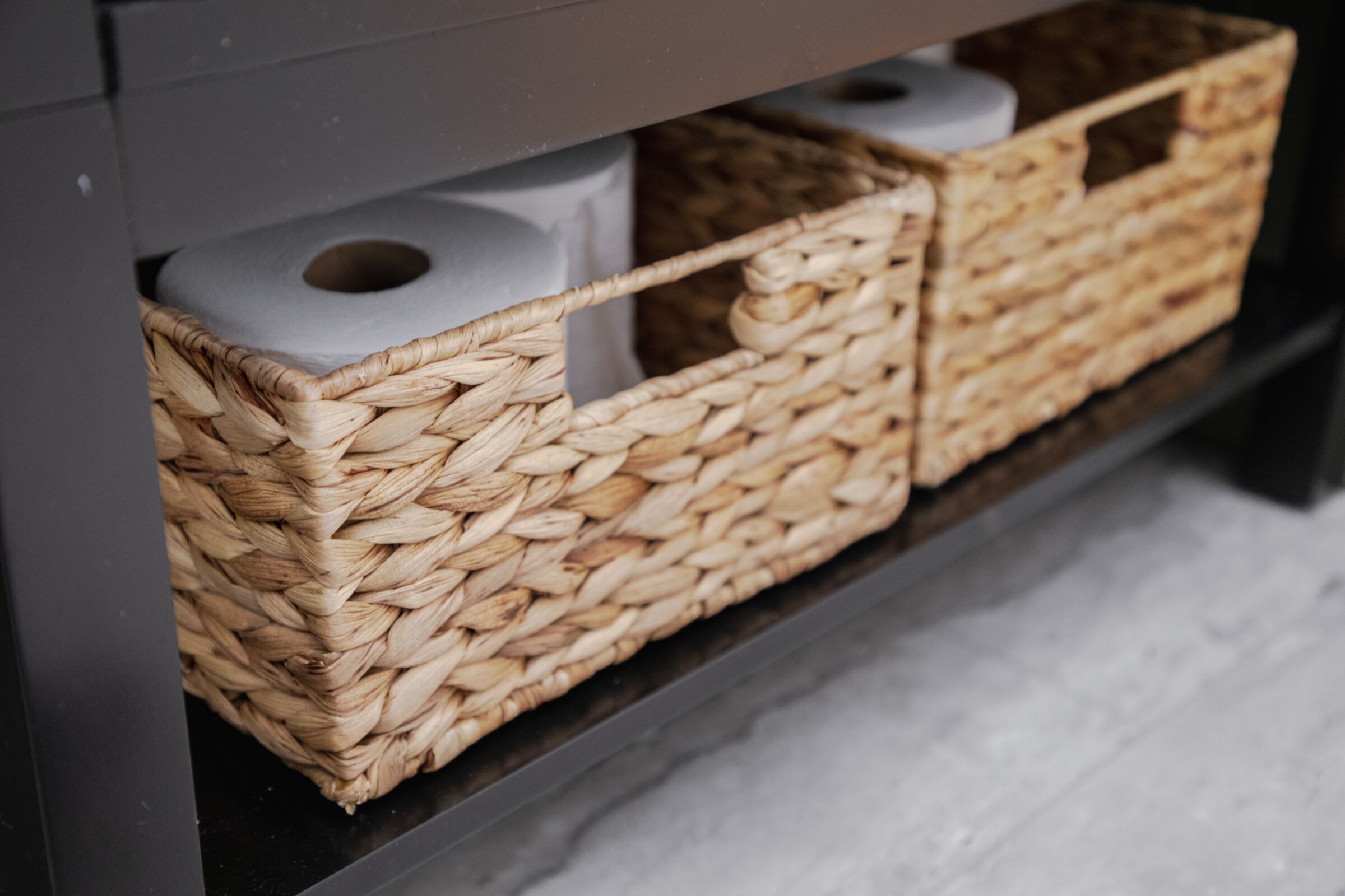 Un espacio de almacenamiento con cestas tejidas que contienen rollos de papel higiénico.