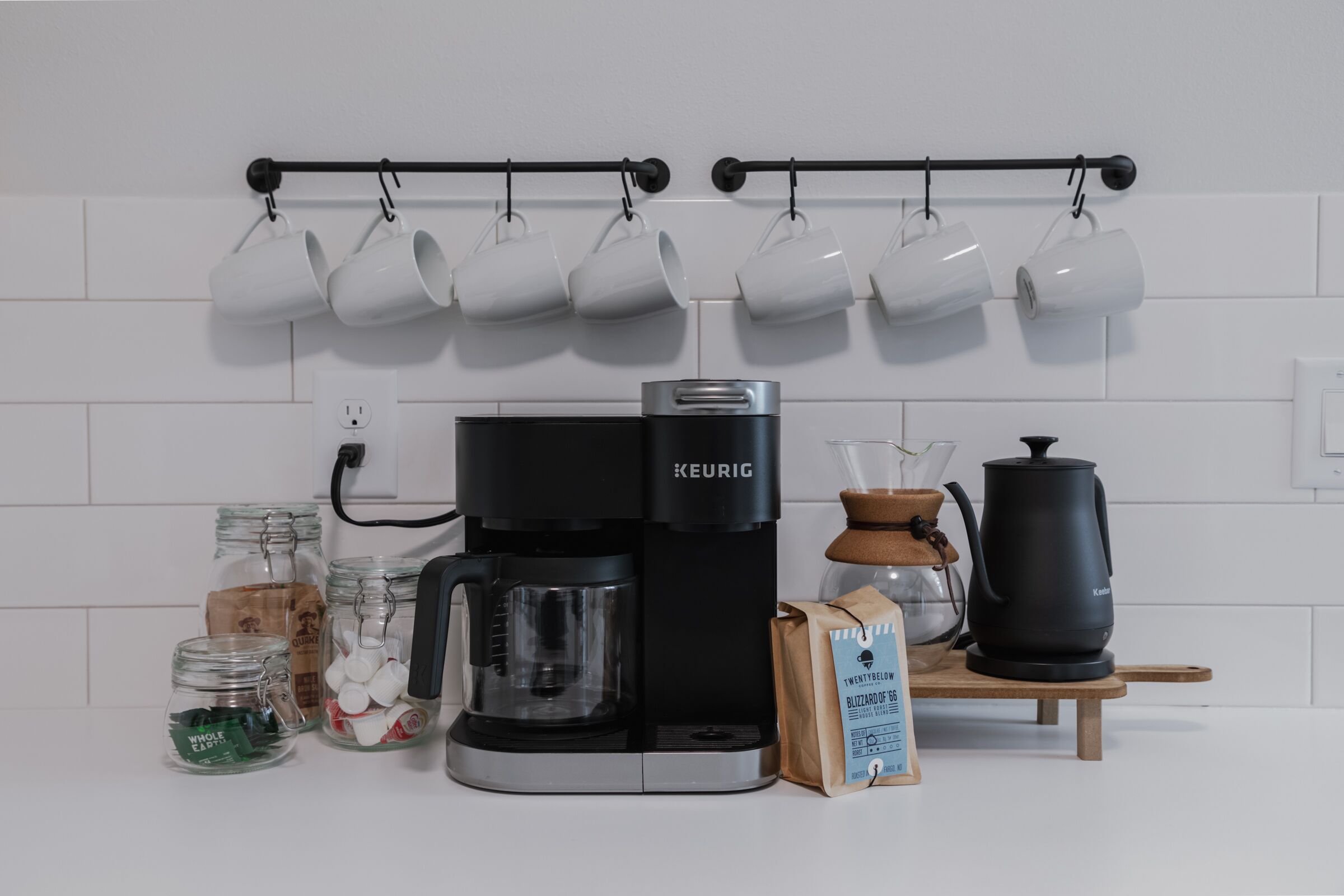 Une cuisine équipée d’une machine à café Keurig, de capsules de café, d’une bouilloire et d’un moulin à café.