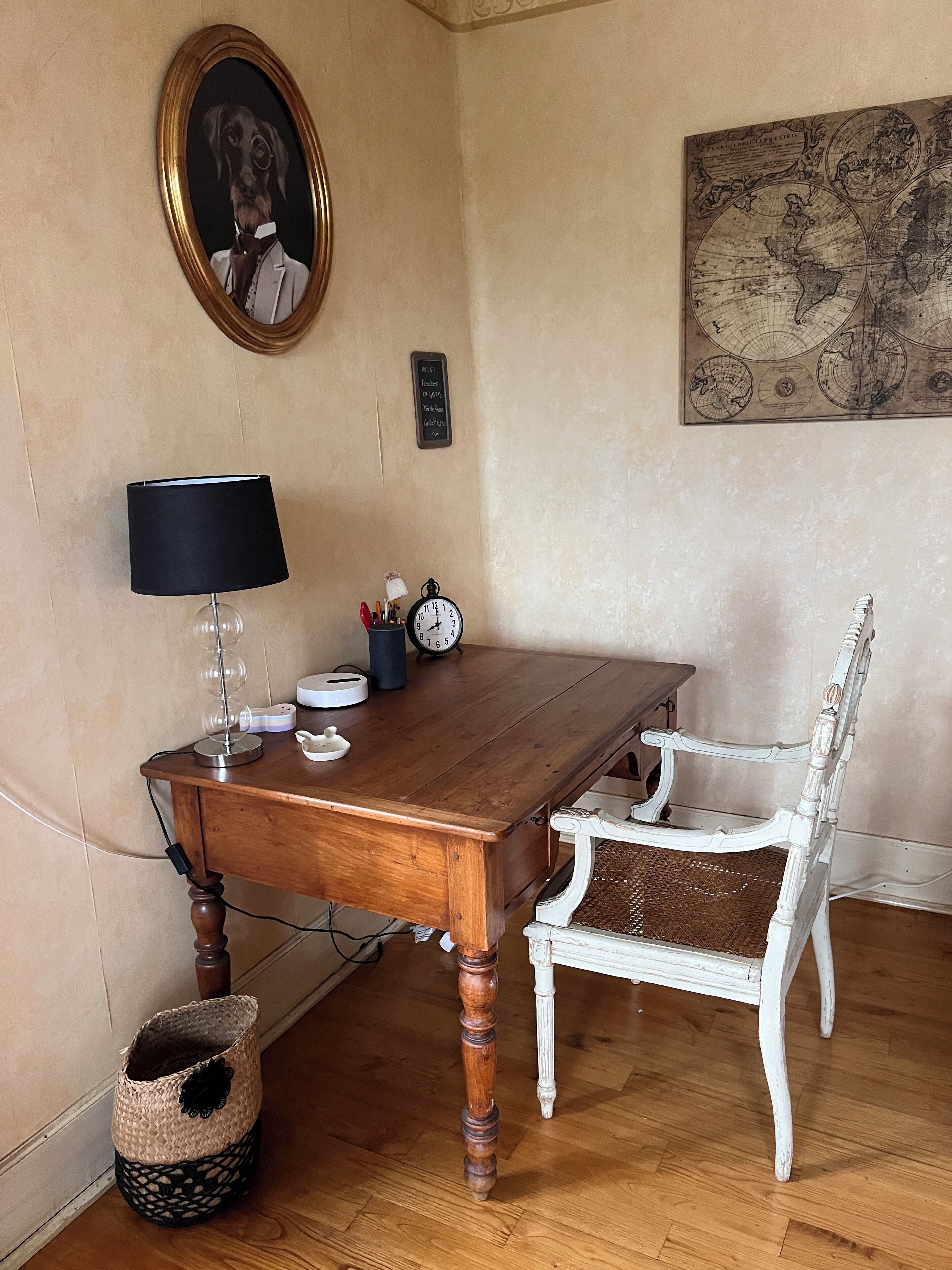 Ein Holztisch mit Lampe, einer Uhr und einem gerahmten Bild an der Wand.