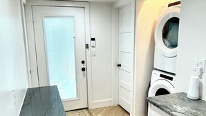 A compact kitchen with a herringbone wood floor, white cabinetry, and a marble countertop.