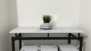 A dining area with a white marble table, three black stools, and two framed artworks on the wall. - Shely’s Apartment#2 (Ceiba)