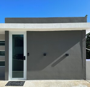 A modern building facade with a glass door, a small window, and a metal vent.