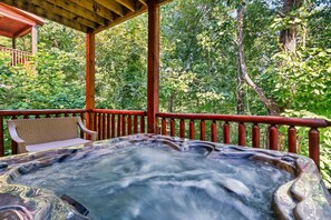 A hot tub under a wooden pergola with a view of a forested area. - Book your Summer Vacation! Log Cabin with 2 King Suites, Hot Tub & Game Room (Sevierville)