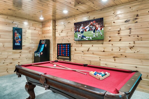 A pool table with a red felt surface, a cue stick, and a set of pool balls. - Book your Summer Vacation! Log Cabin with 2 King Suites, Hot Tub & Game Room (Sevierville)