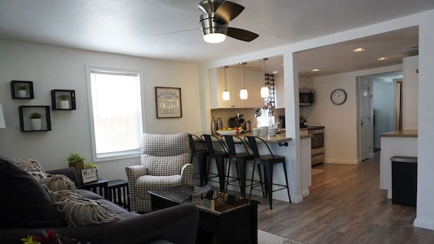 A modern living room with a sofa, a checkered armchair, and a coffee table. There is a kitchen in the background with bar stools and a dining area. - Whole House in N. Denver with hot-tub (Denver)