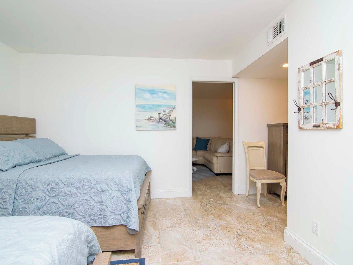 A bedroom with a bed, a chair, and a painting on the wall.
