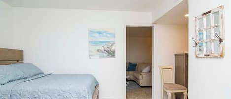 A bedroom with a bed, a chair, and a painting on the wall.