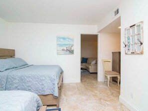 Une chambre à coucher avec un lit, une chaise et un tableau accroché au mur.