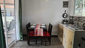 A compact kitchen with a dining table set for four, a small window, and a sliding glass door leading to an outdoor area.