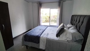 A bedroom with a bed, a window, and a door.