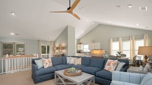 A spacious living room with a large sectional sofa, a wooden coffee table, and a ceiling fan. - SemiSecluded OBX Beach House, Heated Pool&Hot Tub, Beach Access, Pinball, Arcade (Corolla)