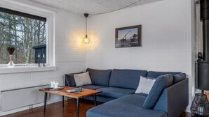 A modern living room with a sectional sofa, a wooden coffee table, a wall-mounted light fixture, and a framed picture.