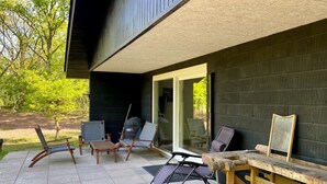A patio with outdoor furniture, a grill, and a wooden table.