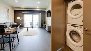 A modern apartment with a dining area, a sofa, a coffee table, a TV, a washing machine, and a balcony with a view. - Cozy 1B1B w/Wi-Fi, Balcony Views, Coffee + Parking (Des Moines)