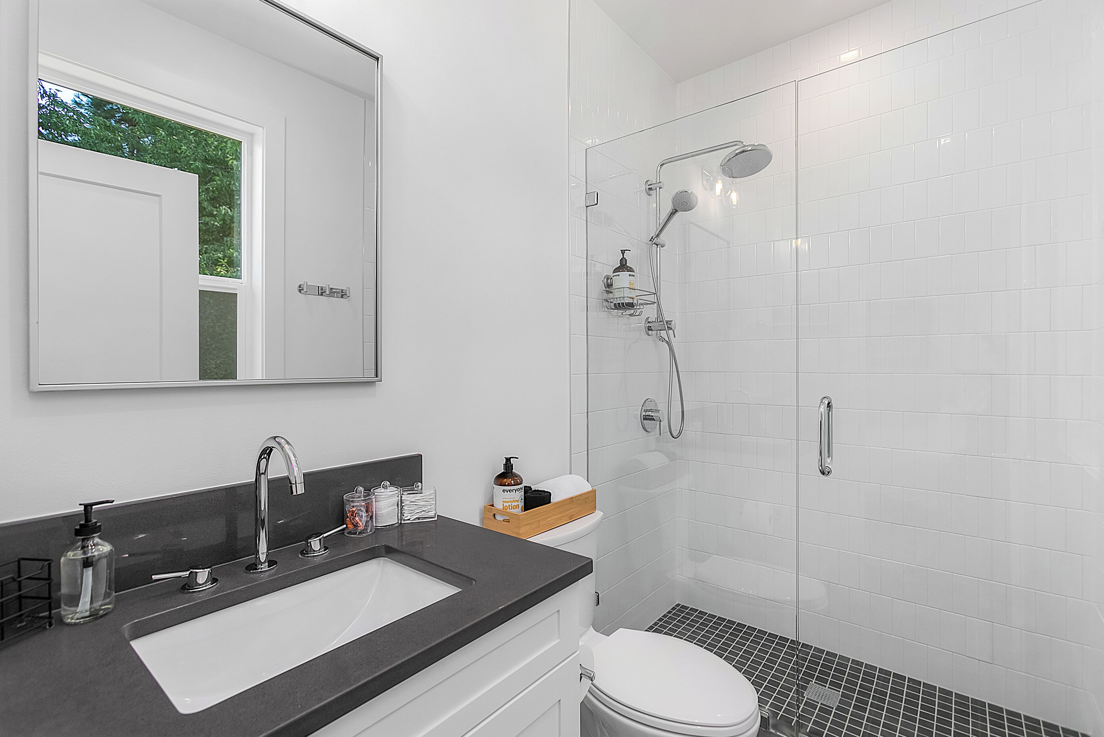 A modern bathroom with a white sink, mirror, and shower.