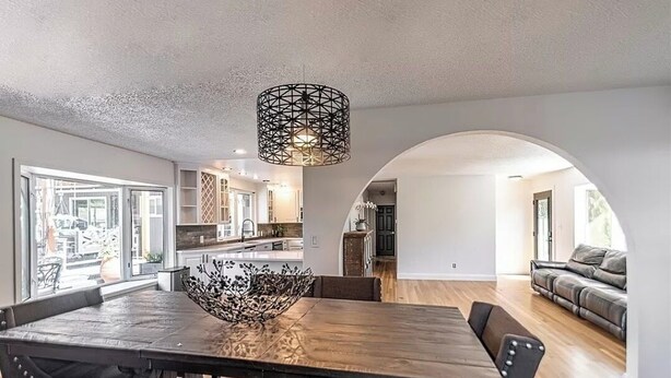A dining area with a wooden table, chairs, and a decorative bowl centerpiece. There is a modern pendant light above the table. - Quiet Modern Stay Near SeaTac & Hospitals (Des Moines)