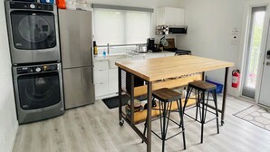 Una cocina compacta con una isla central, electrodomésticos integrados y un extintor.