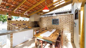 Ulkoterassi, jossa on tiiliseinä, puinen pöytä ja tuolit.