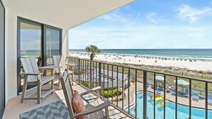 A balcony with a view of a beach and a pool area.