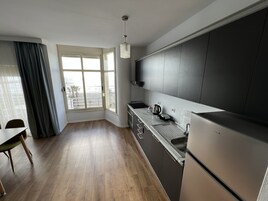 Una cocina moderna con armarios oscuros, un refrigerador de acero inoxidable y un ventanal con vista a la playa.