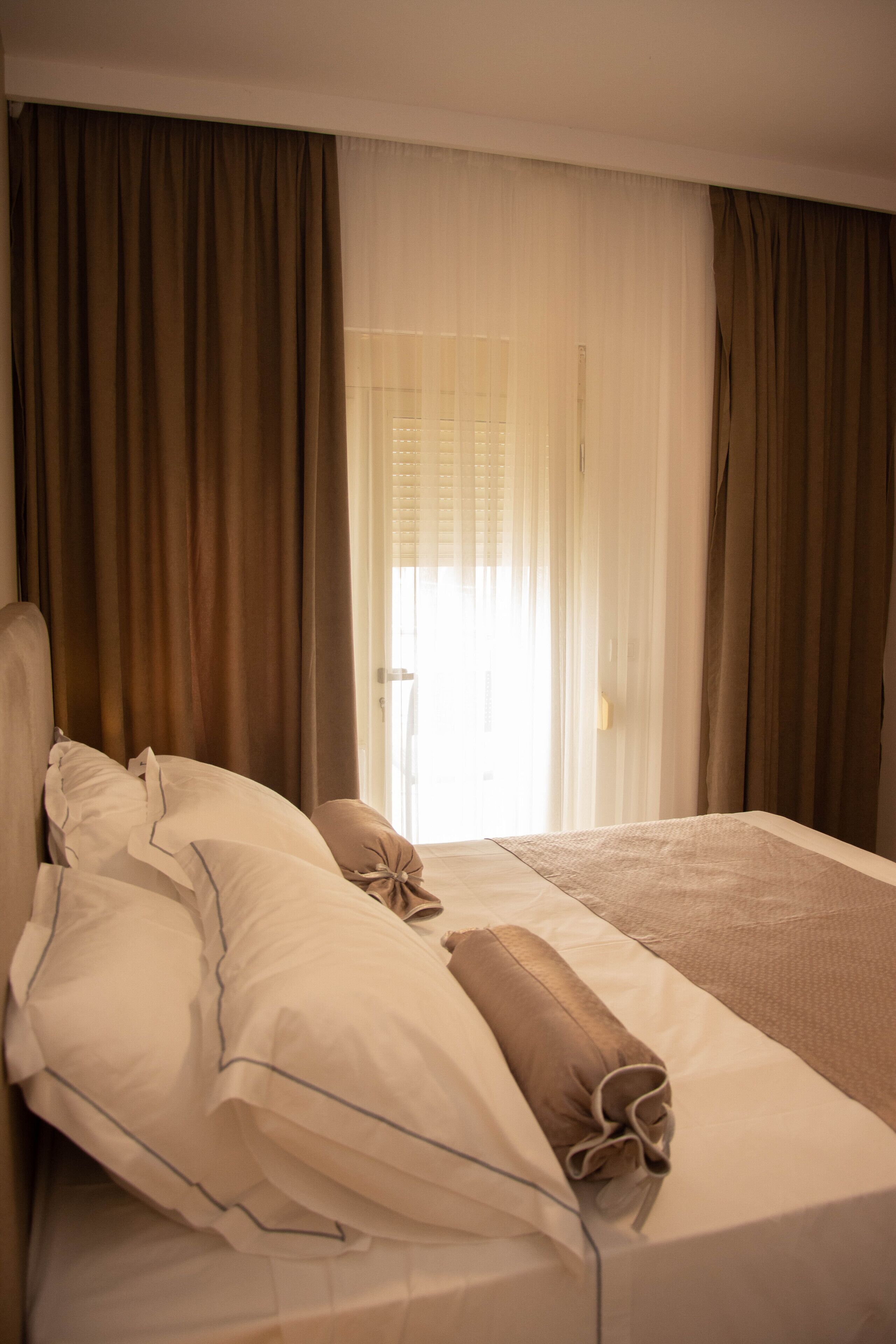 A hotel room with a bed, curtains, and a window with blinds.