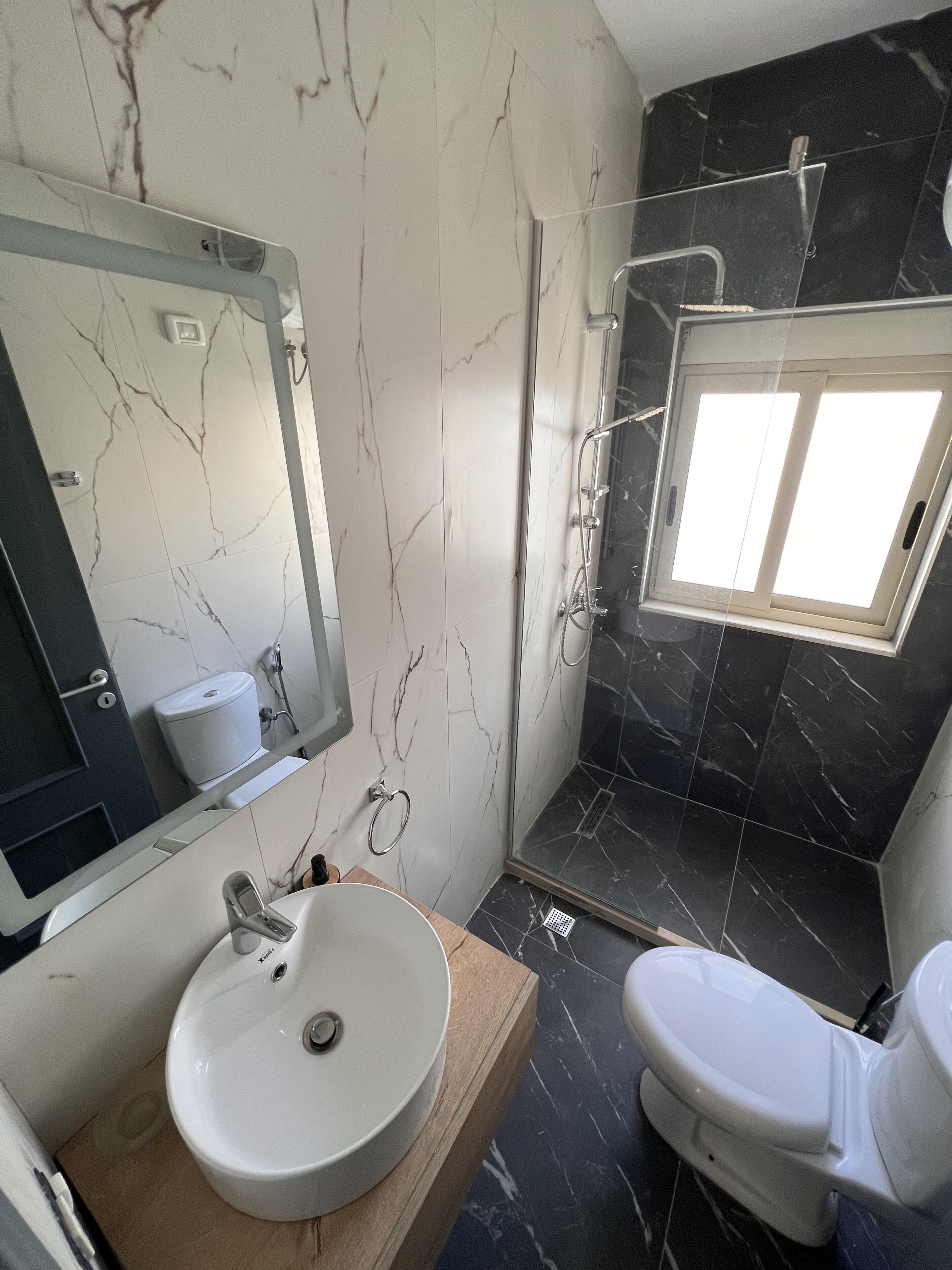 A bathroom with a marble vanity, a toilet, and a shower with a glass door.