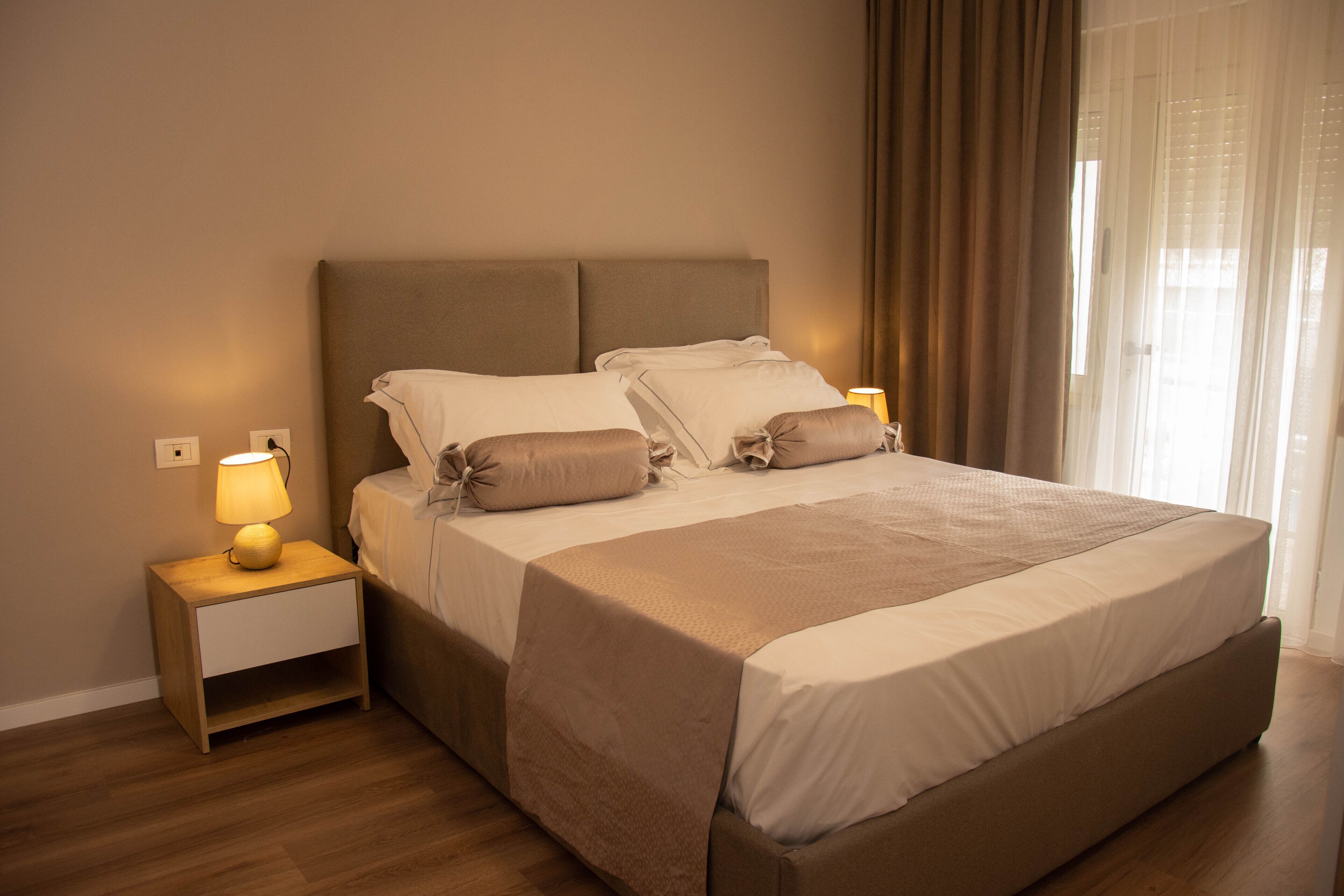 A neatly made bed with a headboard, a bedside lamp, and a nightstand.