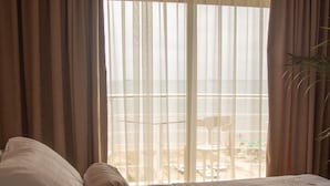 A bedroom with a bed, curtains, and a view of the outdoors. - Wave Beachfront Apartments (Durrës)