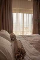 A bedroom with a bed, curtains, and a view of the outdoors.